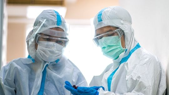 Two nurses in full protective equipment, including masks, gloves and visors 